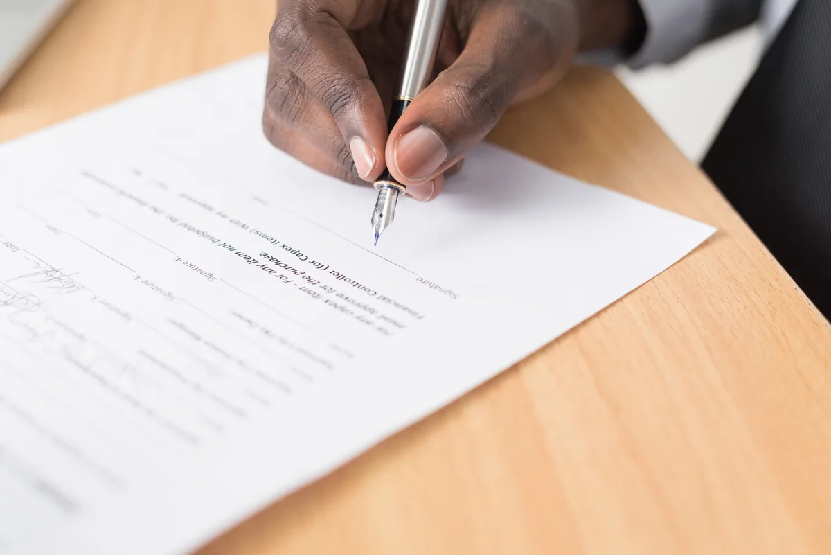 A hand using a fountain pen to complete a paper form.