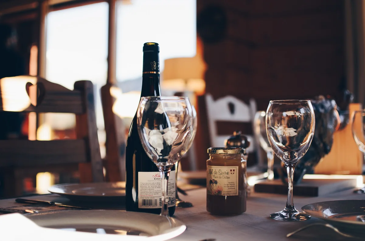 Wine glasses and bottles on a sunlit restaurant table.