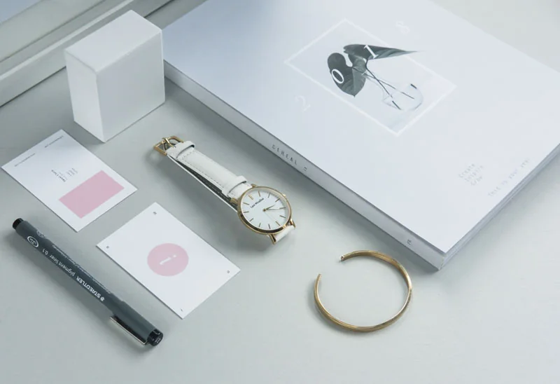 Jewellery, a watch and a small box arranged on a pale surface.
