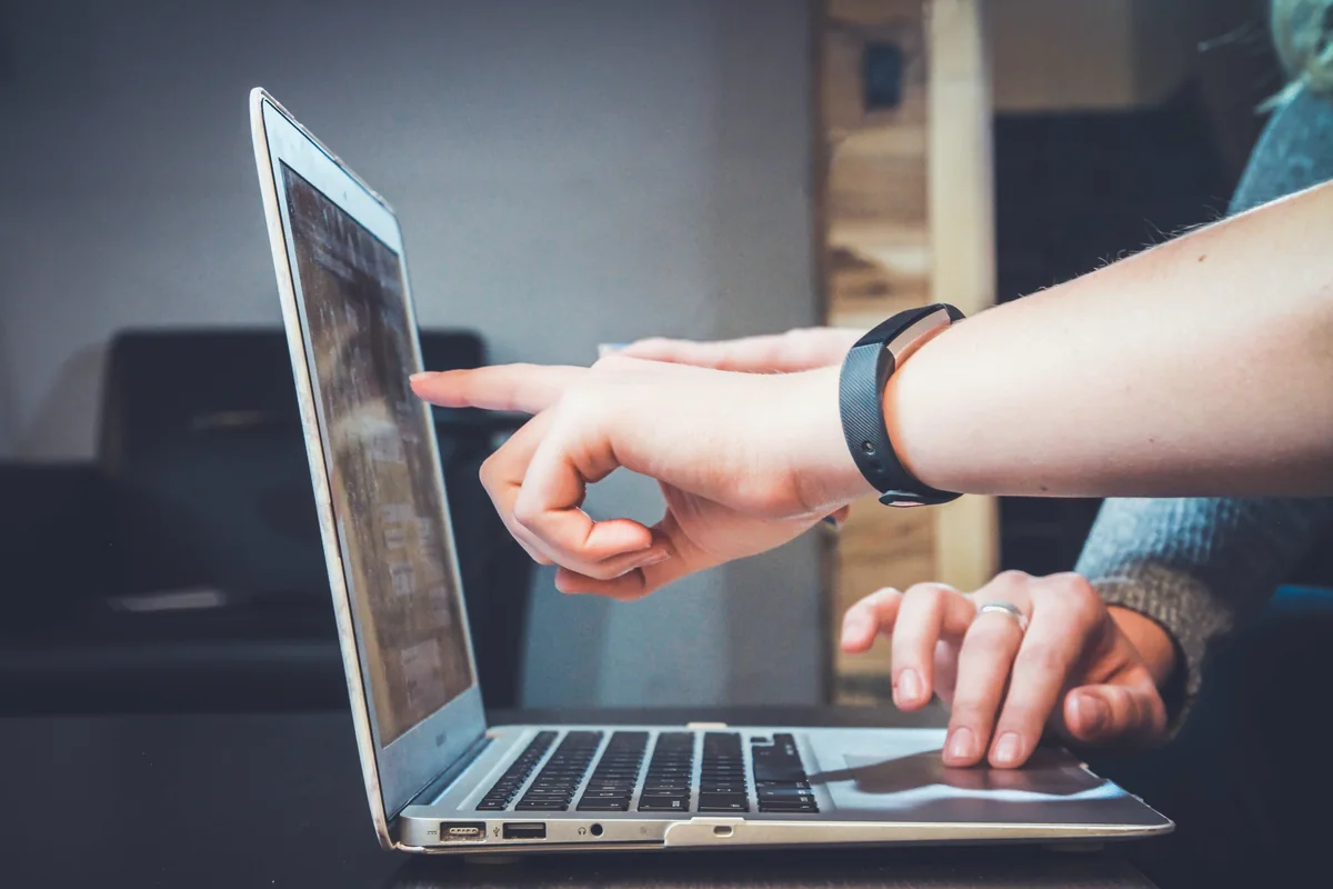 Hands pointing to and using a laptop during a review.