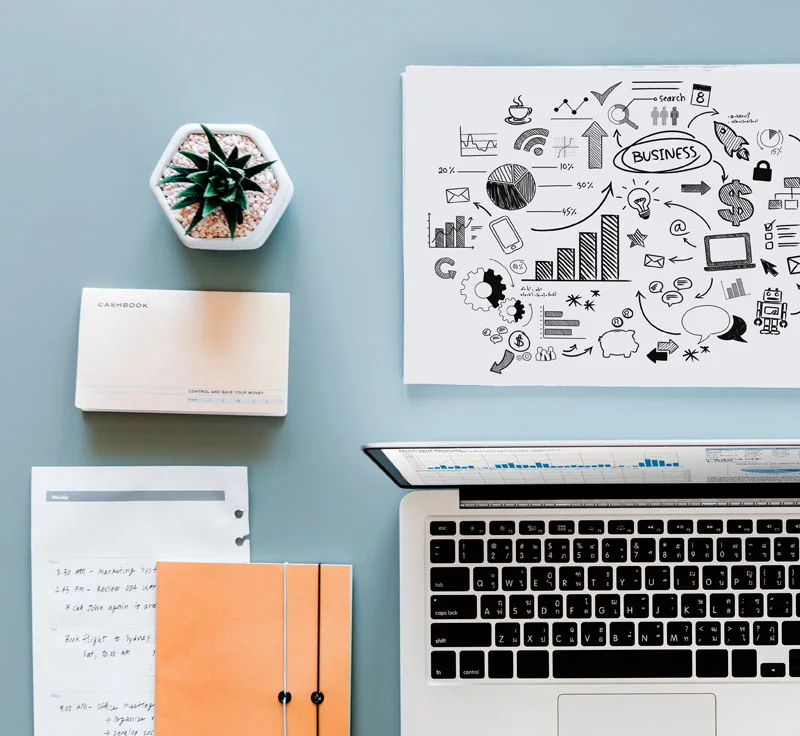 An overhead arrangement of a notebook, laptop and stationery.