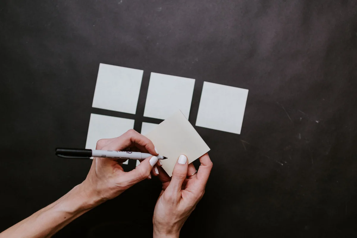 Hands arranging blank cards into groups on a dark table.